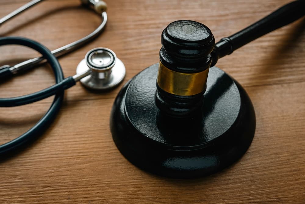 A judge's gavel and a stethoscope on a wooden desk, symbolizing medical-legal matters.