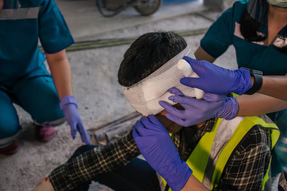 Medical professionals tending to a person with a head injury, applying bandages and providing care.