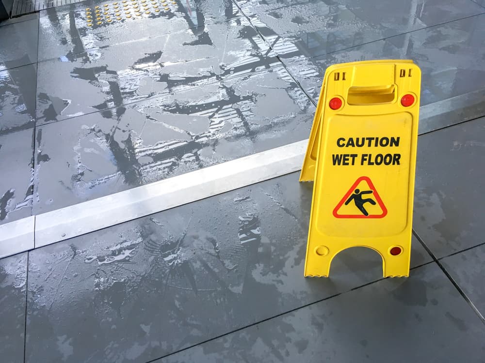 A wet floor with a yellow "Caution Wet Floor" sign placed for safety.