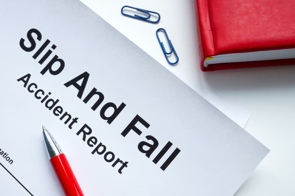 A slip and fall accident report form with a pen and paper clips on a desk.