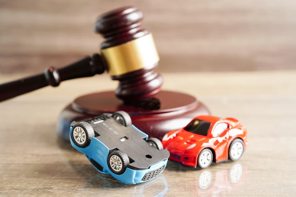 Gavel next to toy cars, one overturned, symbolizing legal action in car accident cases.