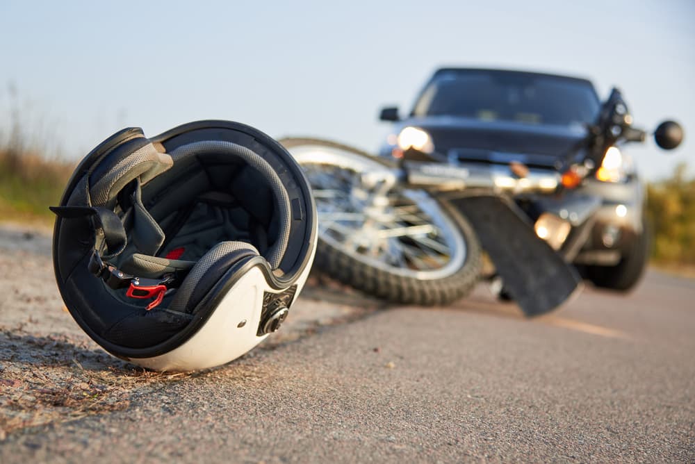 A motorcycle and car crash. Helmet and motorcycle on road,