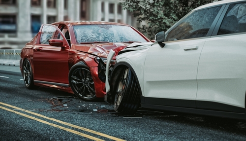 A head-on collision between a red car and a white car on a city street