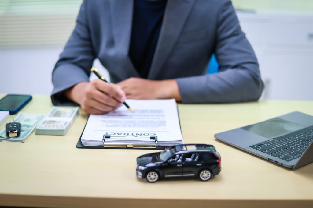 Rideshare accident lawyer reviewing legal documents with a laptop and cash visible on the desk.