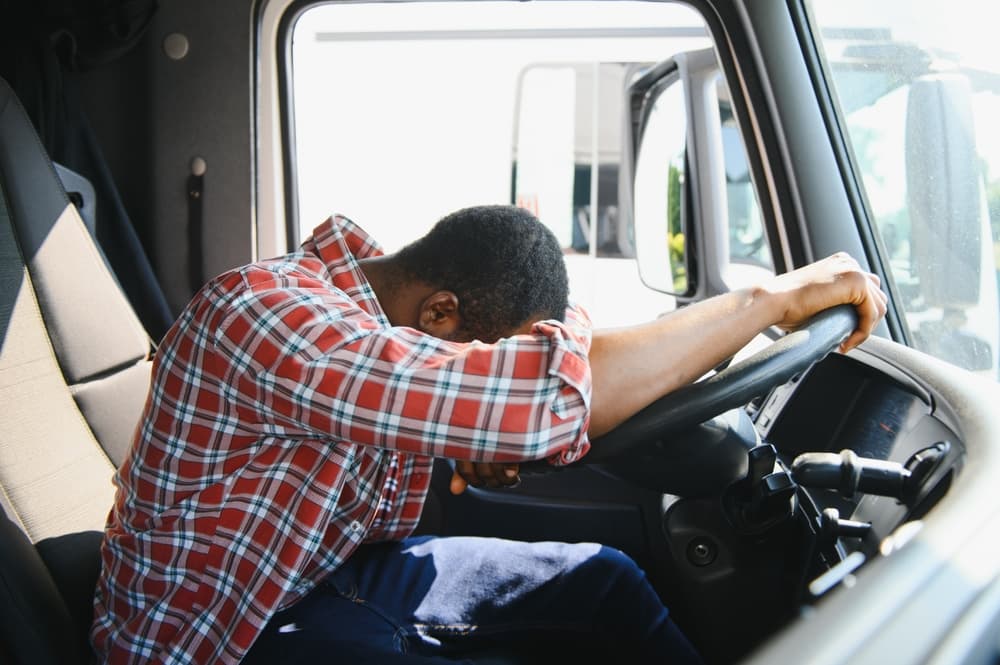 Young African American drunk truck driver is with his vehicle at daytime.